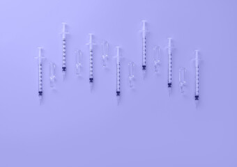 Syringes and ampoules with transparent liquid toned in trendy color of year 2022. Cosmetology and medicine background. Vaccine concept. Flat lay style.