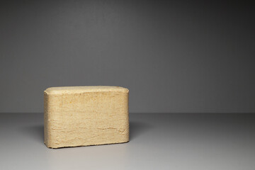 Angular wood chip briquette on a gray background. Solid fuels from coniferous and deciduous wood...