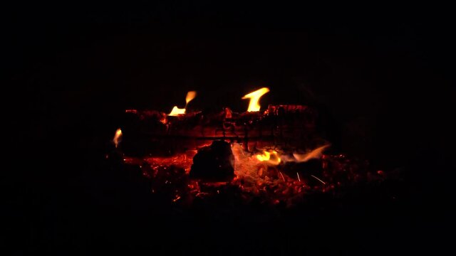 Logs in campfire outside in a pit; close up of exterior campfire, last log on fire before dying out. Orange flames, 628 

