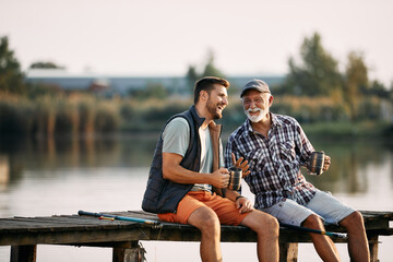Cheerful man and his senior father have fun while fishing from pier. - Powered by Adobe