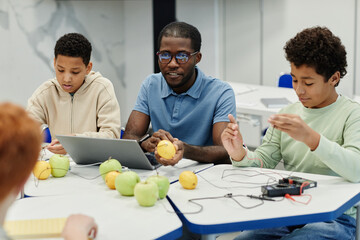 Portrait of male African-American teacher working on science experiments with diverse group of children
