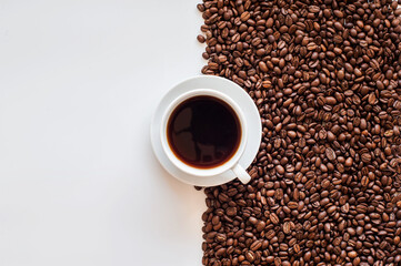 white cup filled with coffee on a background of coffee beans. view from above