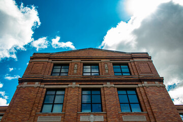 Fototapeta na wymiar blue sky with clouds behind brownstone brick building