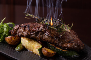 Grilled striploin steak on black dish. steak with fried potatoes and vegetables