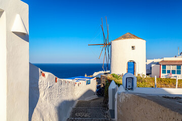 Greece vacation iconic background. Famous windmill in Oia village with traditional white houses during summer sunny day Santorini island, Greece.