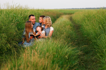  young family with children reading the Bible in nature