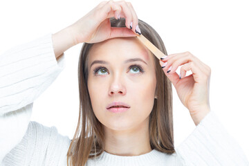 Naklejka premium Close up shot of young sad woman applying adhesive bandage on her forehead after injury isolated on white background