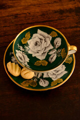 green porcelain coffee cup with biscuit on the saucer, english china cup, green cup,  homemade cookie, luxury porcelain cup, coffee shop, top view