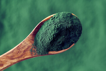 Spirulina powder on a spoon - healthy nutritional supplement