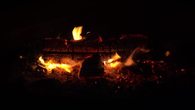 Logs in campfire outside in a pit; close up of exterior campfire, last log on fire before dying out. Orange flames, 628B 
