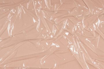 Crumpled wrinkled plastic transparent plastic cellophane on pastel brown color background. Abstract creative texture background