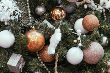 Gold and white christmas balls with sparkles on a snowy christmas tree close-up