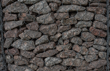 Rocks in cage background texture. Gabions by the river. Rock wall. Stones in cage. Urban landscape design detail. Erosion control.