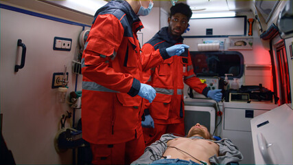 Multi ethnic paramedics giving first aid help to man in emergency car