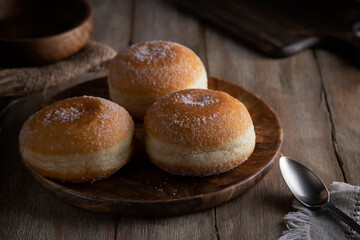 Fresh donuts sprinkled with sugar crumbs on a wooden table