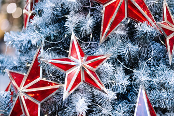 Red christmas balls in the form of stars on a snowy christmas tree close-up