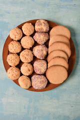Three types of homemade cookies on a round board. Turquoise background. Minimalism.
