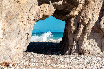 natural arch on the seashore, behind which sea surf can be seen