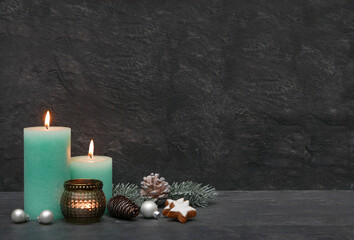Weihnachtshintergrund: Kerzen mit Weihnachtsdekoration vor einer dunklen Wand.