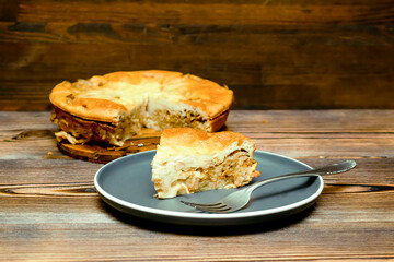 homemade cabbage pie, piece of tart on plate on wooden rustic table. cooking baking pastry receipe. Autumn winter vegetable vegetarian food meal