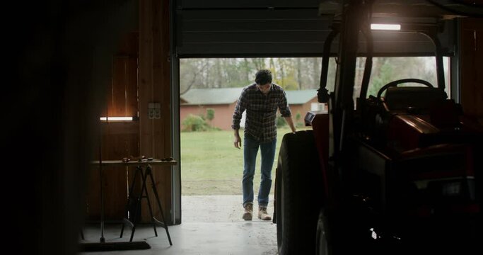 A man walks into an indoor garage approaching a tractor
