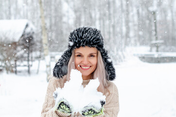 Outdoor portrait of a beautiful and happy smiling girl posing against the snow. Winter, Concept of Christmas, New Year, Winter Holidays. Winter blonde woman outdoors