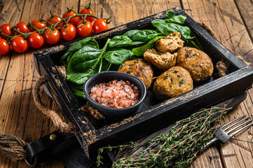 Seafood Fish balls or Fish cake with spinach and herbs in a tray. Wooden background. Top view