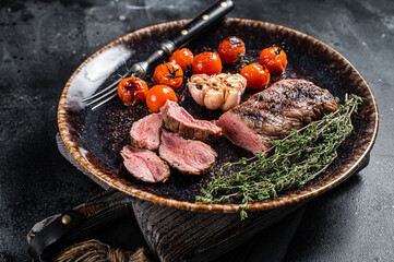 Lamb sirloin fillet meat in plate with grilled tomato, mutton grilled loin steak. Black background....