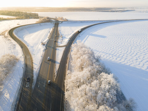 cars on the road surrounded by winter forest. Aerial view