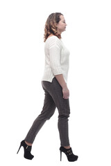 attractive young woman in a white jumper striding forward.