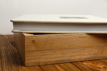 fabric closed photo album on wooden box. stylish box with photoalbum on wooden background close up. square photobook with space for text on  table top view.  beige photo book pages