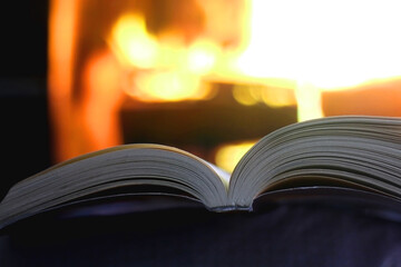 Open book in front of a fireplace. Selective focus.
