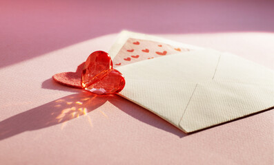 Open envelope, felt and glass heart on a pink background.