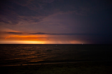 Fototapeta na wymiar Lightning bolts illuminate the sky at night in the sea