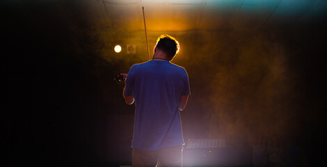 View from the back of a man playing the violin on stage