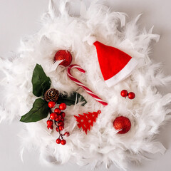 Composition with Christmas decorations on white feathers garland. Winter holidays concept.