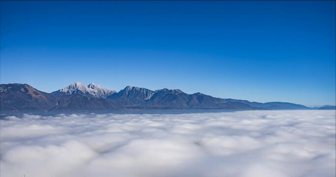 Time lapse of cloud inversion or temperature inversion. Thick layer of mist clinging to the ground in Slovenia. Sea of cloud with mountain tops rising out of the fog. Aerial or elevated view. Static