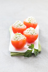Fresh tomatoes stuffed with cottage cheese and parsley on a serving tray on a light background