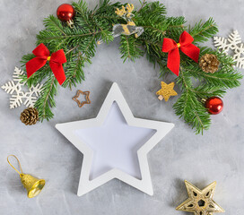 New year mockup: christmas tree branches with white star shaped photo frame on grey background. Holidays concept. Text space, copy space