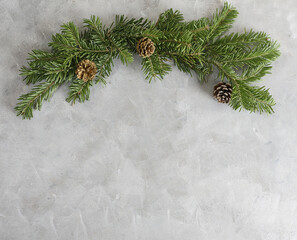 New year frame: christmas tree branches with fir cones on grey background. Holidays, nature concept. Text space