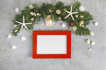 New year mockup: decorated with seashells and starfich pine tree branches with red photo frame on grey background. Tropical christmas, holidays concept. Text space
