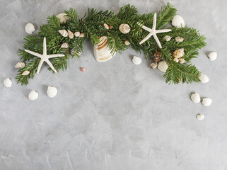New year frame:  top view flat lay pine tree branches with seashells and starfish on grey background. Tropical christmas, holidays concept. Text space