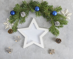 New year mockup: decorated christmas tree branches with white star shaped photo frame on grey background. Holidays concept. Text space