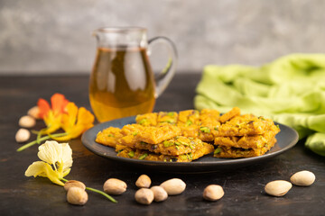 Traditional iranian dessert sohan with glass of green tea on a black concrete background. side view, close up.