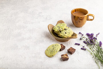Green cookies with chocolate and mint with cup of coffee on gray concrete background. side view, copy space.