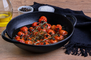 iron casserole with confit tomatoes on wood table