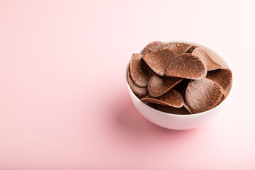 Chocolate chips on pink pastel background. side view, copy space.