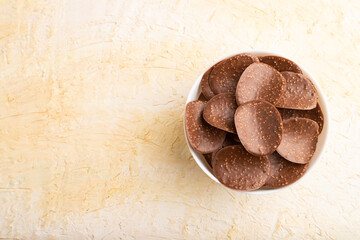 Chocolate chips on a beige concrete background. top view, copy space.