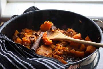 A pot of pumpkin bredie stew. South African dish made with pumpkin or butternut squash chunks and meat. With cinnamon sticks