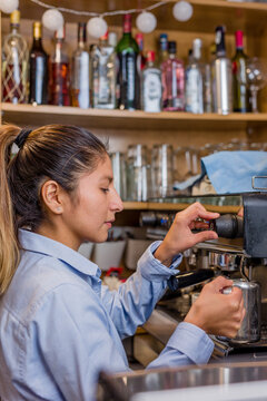 Latin barista prepare an expresso with coffee machine. Young Peruvian woman lifestyle business